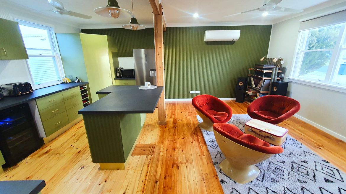 Reclaimed White Cypress feature beams replacing the original wall, and compliment the freshly polished floorboards. With Laminex Surround scallop panelling, in Dulux Olive Blend, used for the feature wall and island bench, and Dulux Renovation Range painted kitchen cabinetry in Nicks Nook