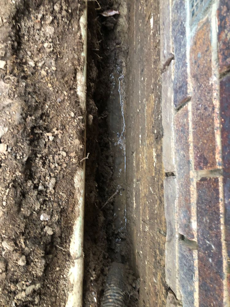 Exterior trench dug next to house had dried out but recent rain shower caused water laying in trench and seepage into house again